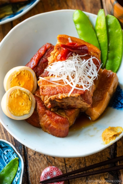 A bowl containing Kakuni, Japanese braised pork belly, served with julienned white scallion, boiled egg, and karashi mustard.