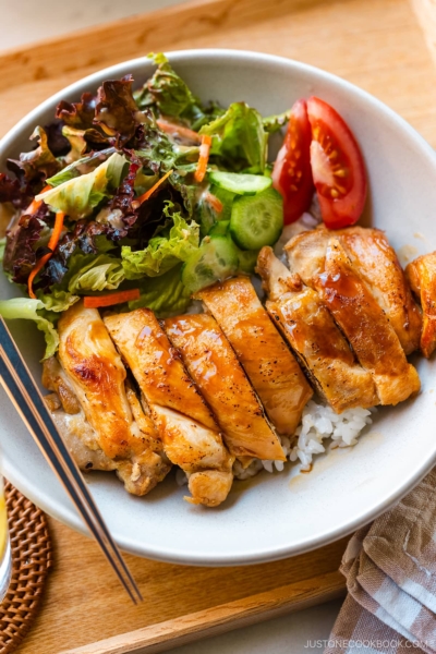 A bowl containing Chicken Teriyaki glazed with homemade teriyaki sauce on the bed of steamed rice.