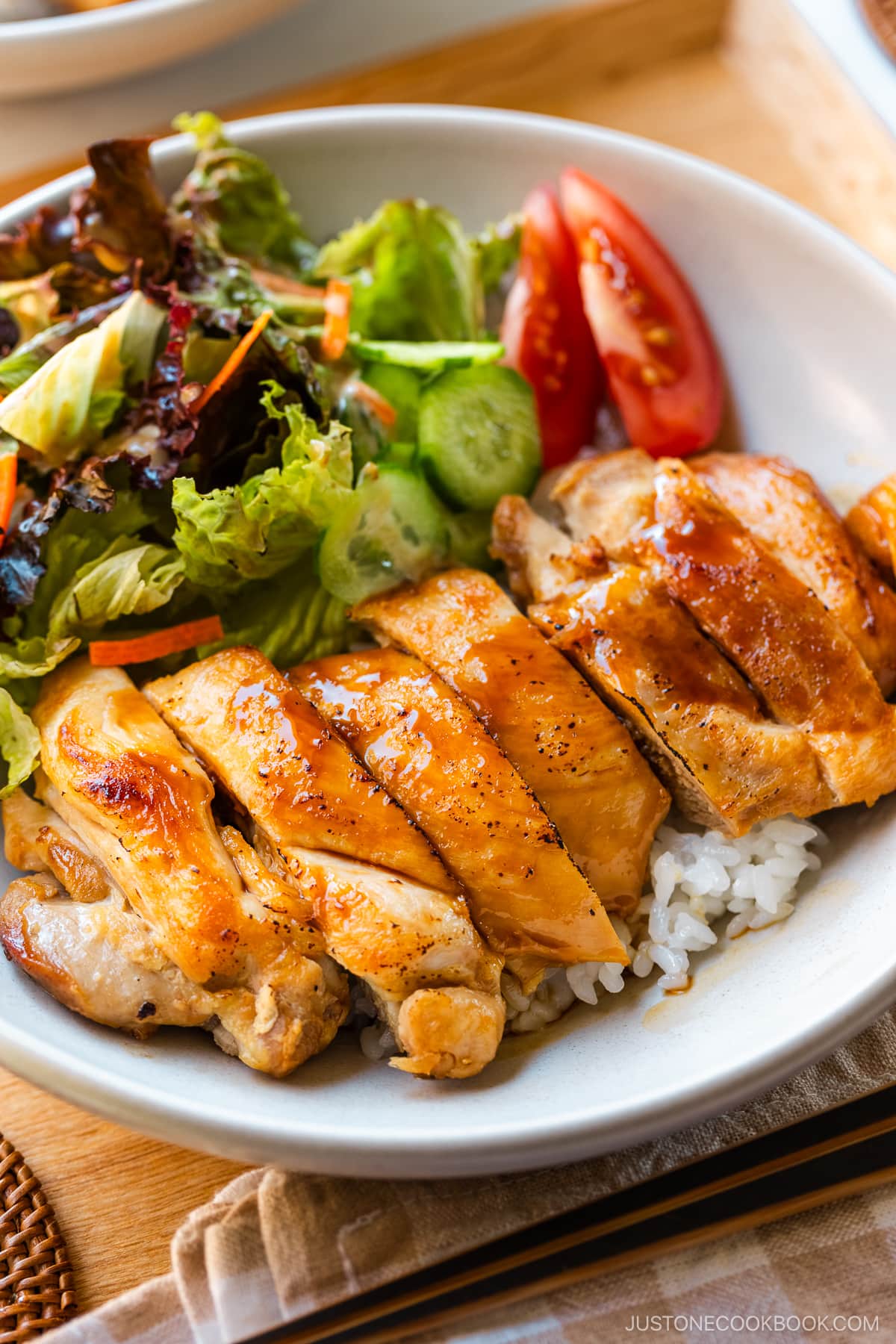 A bowl containing Chicken Teriyaki glazed with homemade teriyaki sauce on the bed of steamed rice.