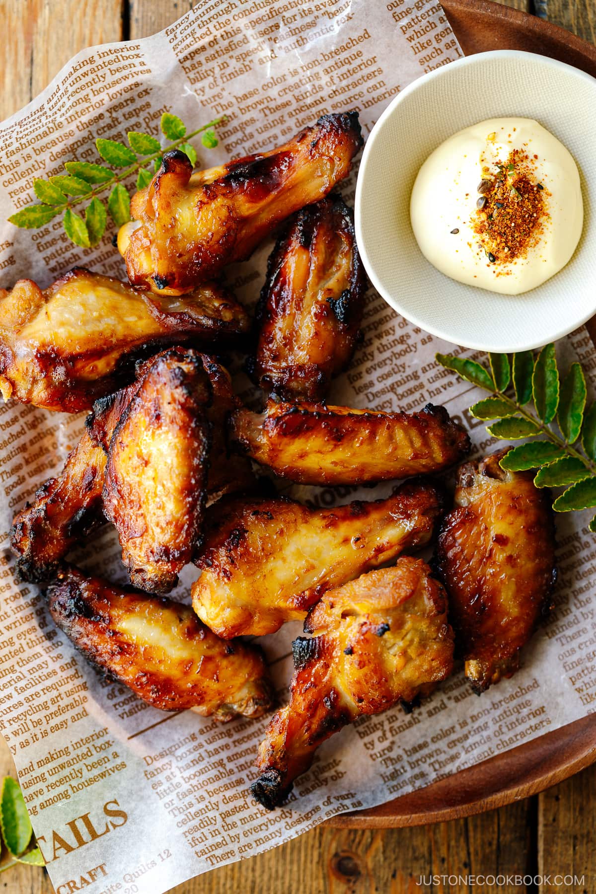 A round wooden plate containing Garlic Miso Chicken Wings.