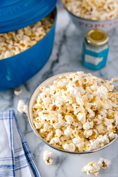 A bowl and Dutch oven containing popcorn with truffle salt seasoning.