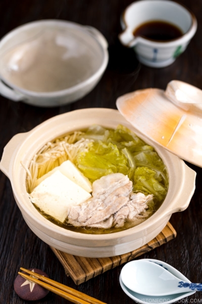 A donabe containing pork, cabbage, tofu, and mushrooms in a kombu broth.