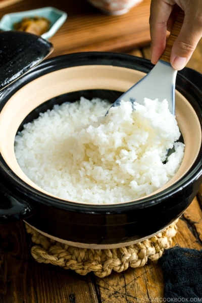 Rice paddle scooping rice out of the kamadosan donabe containing perfectly cooked Japanese rice.