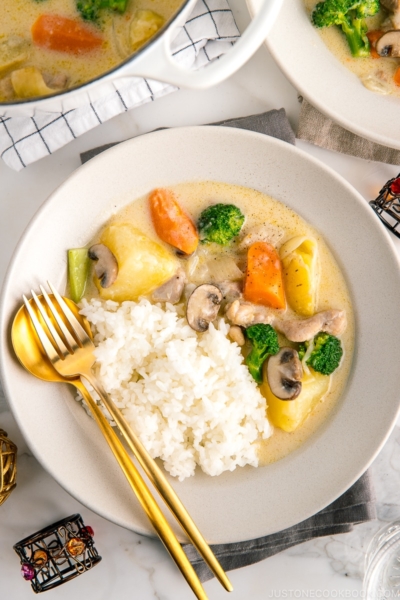 A beige ceramic dish containing steamed rice and Japanese cream stew.