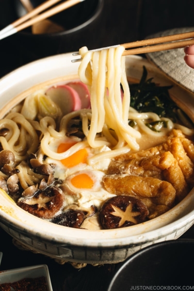 A donabe containing udon noodles, chicken, fish cakes, deep fried tofu, mushrooms, and leeks in a hearty miso broth.