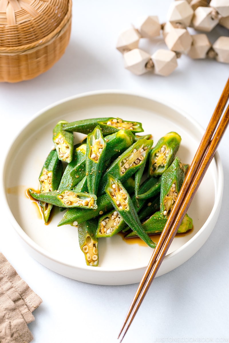 A white plate containing okra with ginger soy sauce.