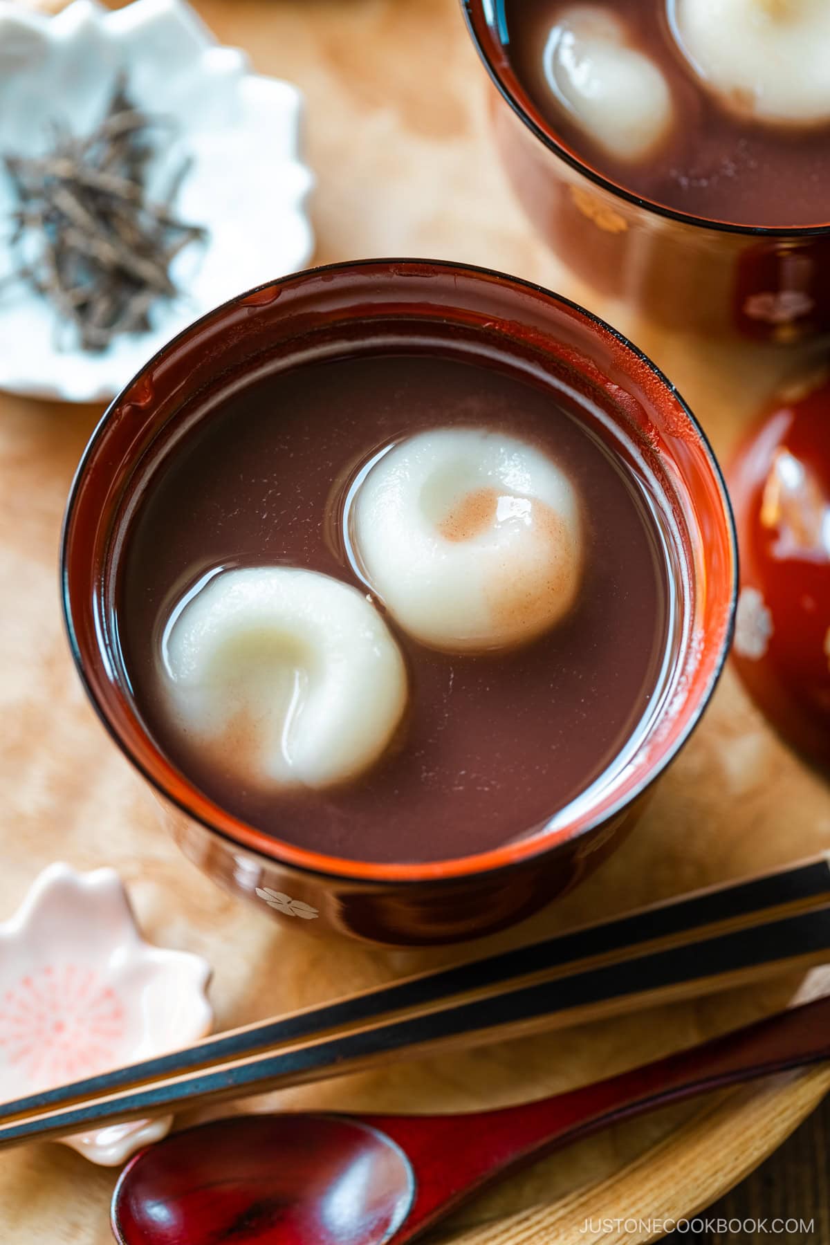 Red lacquered bowls containing red bean soup with mochi balls.