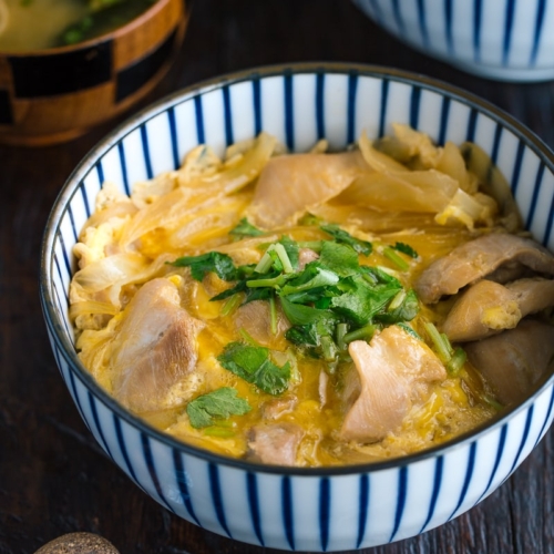 A Japanese blue and white bowl containing Oyakodon (chicken & egg bowl) served with miso soup.