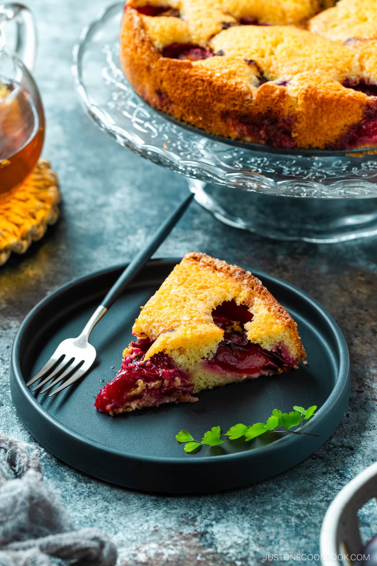 A slice of plum cake on the black ceramic plate.