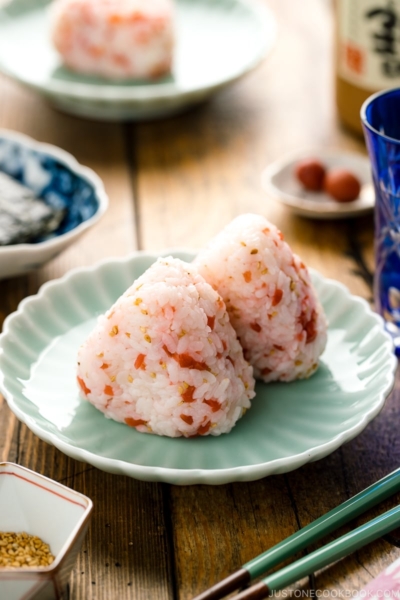 Plum rice balls on a light green plate served with nori seaweed.