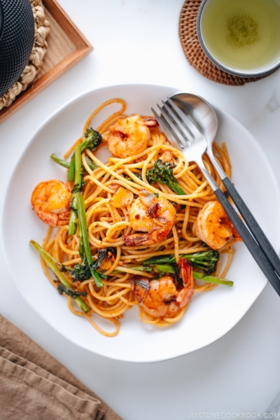 A white plate containing Japanese Pasta with Shrimp and Broccolini.