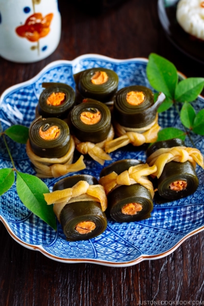 A blue Japanese plate containing salmon kombu rolls.