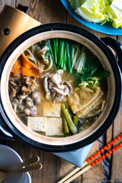 A Japanese earthenware pot (Donabe) containing vegetables, tofu, and pork cooked in sesame and miso based soup broth.