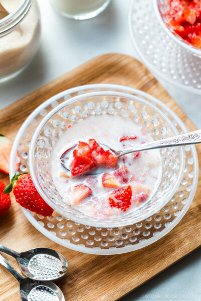 A glass bowl containing Japanese strawberry milk dessert with chunks of fresh strawberries.