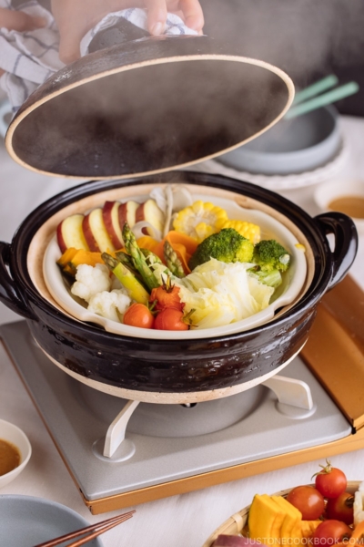 Steamed vegetables on donabe steamer along with dipping sauce.