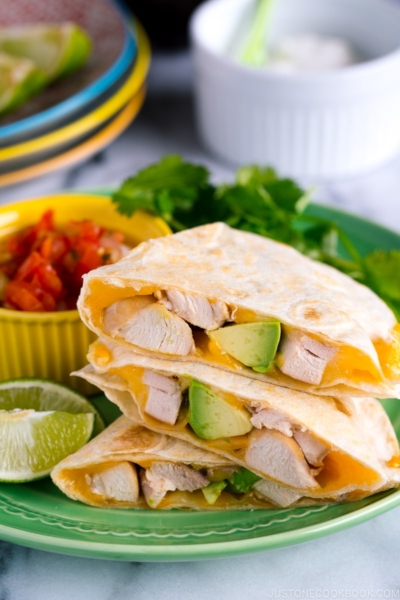 A green plate containing teriyaki chicken quesadilla.