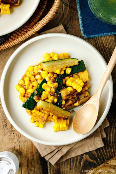 A white plate containing zucchini corn stir fry seasoned with miso butter.